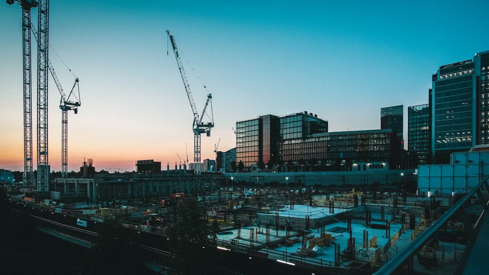 Urban construction site at sunset with cranes and modern office buildings in the background - Causeway Skillguard